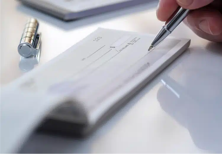 Close-up of a person signing a check for child support