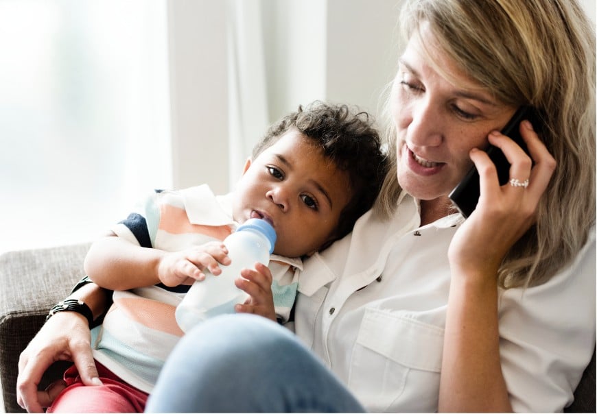A parent on the phone while holding a child
