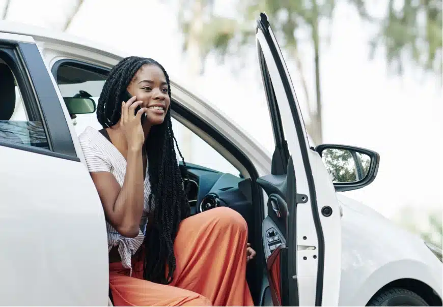 A woman getting out of a car while on the phone