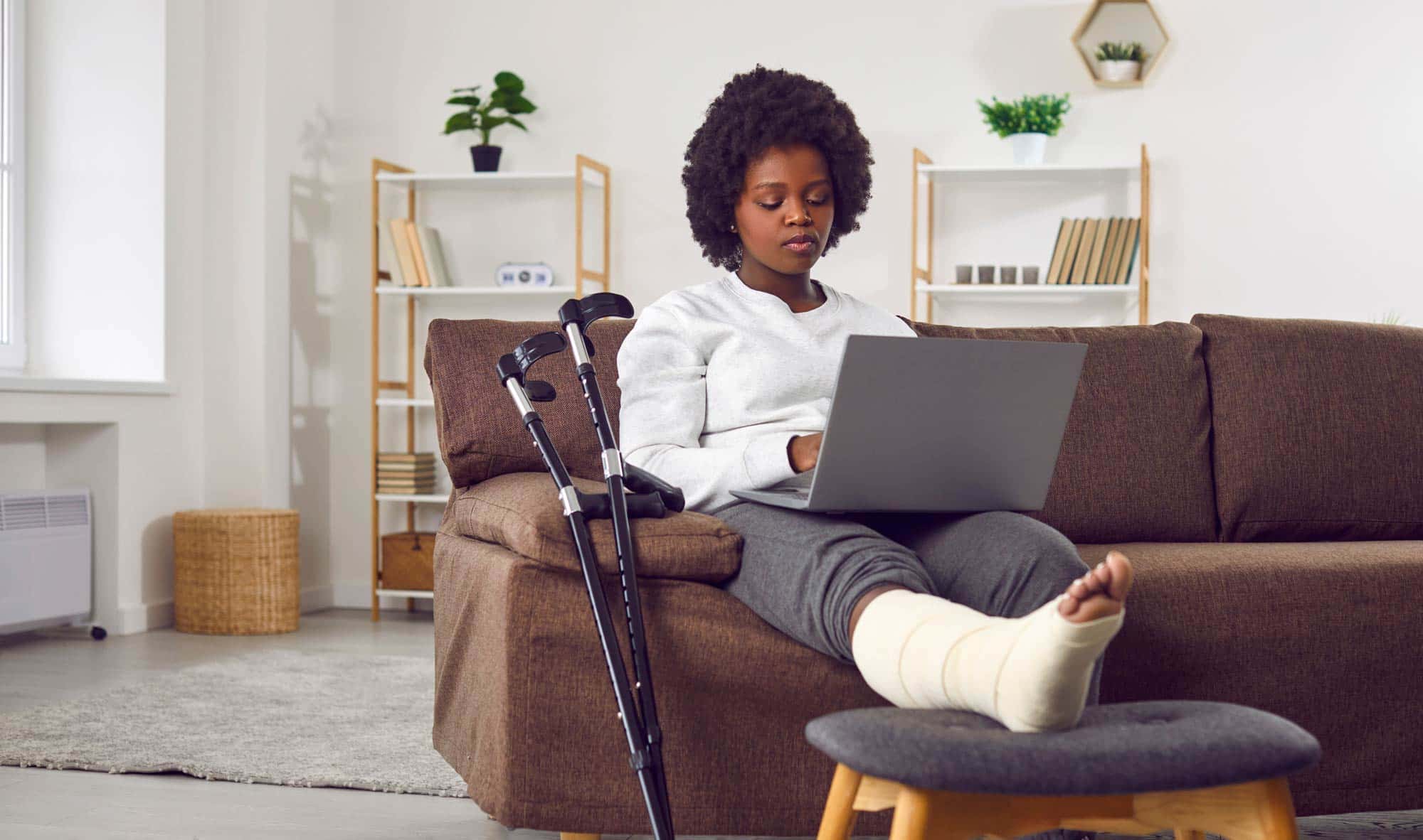 A woman with a leg injury doing research on a laptop