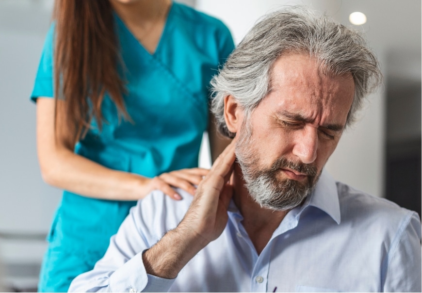 A man showing a medical professional where he has a pain in his neck